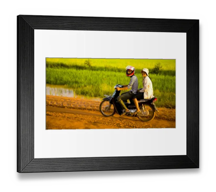 Framed Print : Girls riding along a dirt road in Cambodia