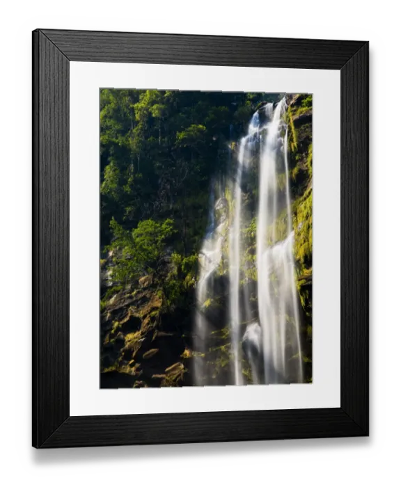 Framed Print : Laos, Ban Na Hin, Waterfall. Shafts of light pass through vegetation hanging to the rock face near a Framed Print : Laos, Ban Na Hin, Waterfall. Shafts of light pass through vegetation hanging to the rock face near a