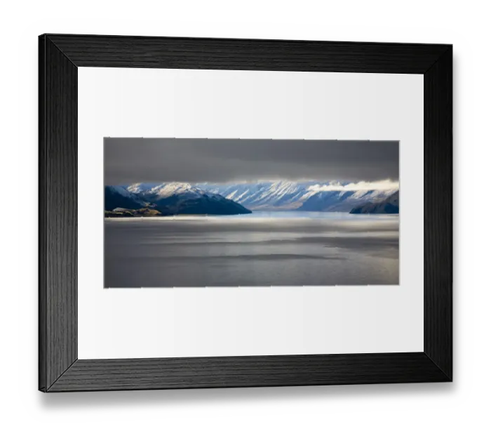 Framed Print : New Zealand, Otago, Lake Hawea. The Southern Alps revealed through a small gap between dense snow clouds and the surface of