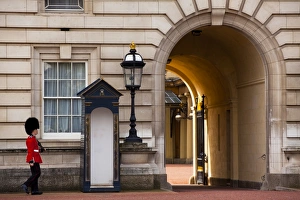 England, Greater London, City of Westminster. Queens Guard walking towards archway outside Buckingham