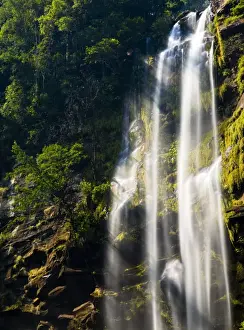 Cascade Prints: Laos, Ban Na Hin, Waterfall. Shafts of light pass through vegetation hanging to the rock face near a