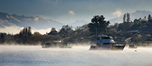 New Zealand, Otago, Lake Wanaka. Boats moored on Lake Wanaka engulfed by rising mist on a cold